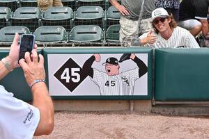 A security guard takes a photo of a fan near the recently installed memorial of the late Chicago White Sox pitcher Bobby Jenks prior to a game against the Cleveland Guardians at Rate Field. editorial_image
