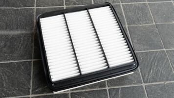 Top view of new engine air filter of car. Cloth panels are covered with clean white. Placed on a black tiled floor. photo