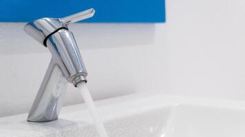 Taps that are turned on. Clean water flowing out of the faucet. A beautiful and clean bathroom sink. photo