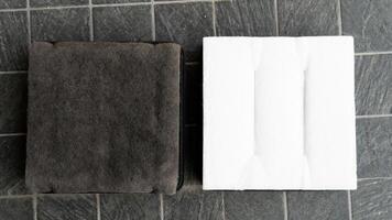 Backside of old and new filters. Comparison between new and old is different. Placed on a black tiled floor. photo