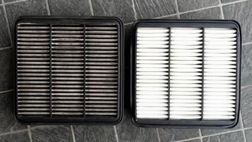 Front of old and new filters. Comparison between new and old is different. Placed on a black tiled floor. photo