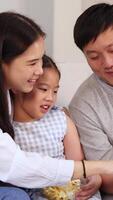 A family enjoys reading together, sharing smiles and popcorn in a cozy setting with warm lighting video