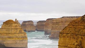 A serene view of the Twelve Apostles rock formations under overcast skies, captured along the Great Ocean Road in Australia video