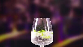 A mojito cocktail is prepared with lime and mint in a lively, colorful environment. Bright lighting enhances the refreshing appearance video