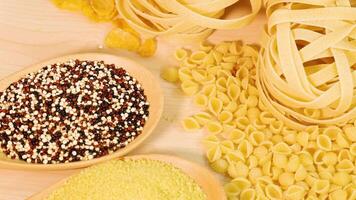 Various pasta types and grains arranged on a light wooden surface with warm lighting video