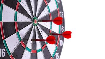 Side view of close up red darts hitting target on dartboard isolated on white background. Business success, precision, accuracy, focus, strategic planning, leadership, marketing concept. photo