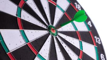 Close up of green dart hitting bullseye on dartboard with side view angle. Business target, precision, focus, accuracy, success concept. Isolated goal achievement symbol. photo