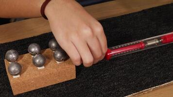 A hand uses a spring scale to measure friction on a carpet, pulling a weighted block across the surface video