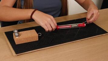 Hands use a spring scale to measure frictional force on a block. Indoor setting, close-up view, natural lighting video