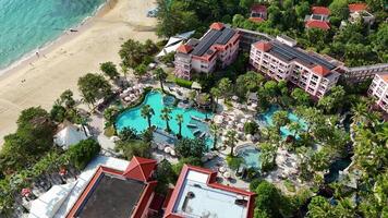 Aerial footage of a luxury resort in Phuket, Thailand, showcasing pools, lush greenery, and beachfront under bright daylight video