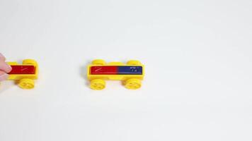 Hands manipulate colorful magnetic toy cars on a white surface, illustrating magnetic attraction and repulsion principles video