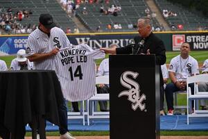 Cardinal Blase Cupich, Archbishop of Chicago, presents Paul Konerko, member of the 2005 World Series Chicago White Sox, with a jersey signed by Pope Leo XIV prior to a game against the Cleveland Guardians at Rate Field. editorial_image