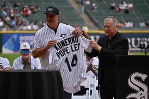 Cardinal Blase Cupich, Archbishop of Chicago, presents Paul Konerko, member of the 2005 World Series Chicago White Sox, with a jersey signed by Pope Leo XIV prior to a game against the Cleveland Guardians at Rate Field. editorial_image