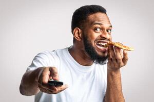 Man eating pizza with remote control photo