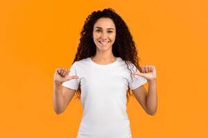 Look At Me. Happy Lady Pointing Fingers Thumbs At Herself Posing Standing On Yellow Background, Smiling To Camera. Studio Shot. Choose Me. Self-Confidence Concept. Panorama photo