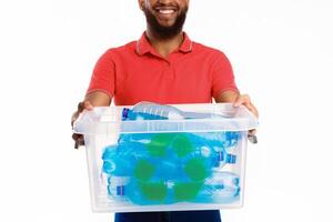 Waste Sorting And Recycling. African American Man Holding Box With Used Plastic Bottles Standing On White Studio Background. Trash Classification, Wasted Plastic Disposal Concept. Cropped photo