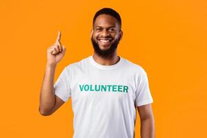 Great Idea. African American Volunteer Guy Pointing Finger Up Smiling To Camera Standing Over Yellow Studio Background. Male Activist Having Eureka Moment. Volunteering Advertisement photo