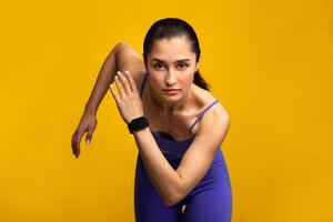 Healthy Lifestyle. Front portrait of confident young lady in blue sportswear running towards camera. Determined female jogging and sprinting isolated over orange studio background wall photo