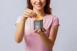Food Waste Recycling. Conceptual Image With Young Woman Holding Small Grey Toy Recycle Bin Container, Unrecognizable Lady Standing Over Light Studio Background, Closeup With Free Space photo