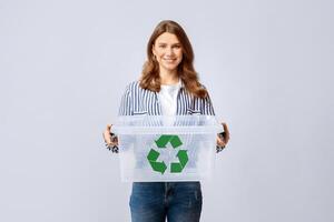 Smiling Young Woman Holding Empty Plastic Container With Green Recycle Sign Icon, Positive Millennial Woman Enjoying Zero Waste Living And Garbage Sorting, Standing Over Light Background, Copy Space photo