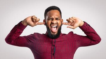 Mad Black Man Shouting Covering Ears With Hands And Closing Eyes Posing Over White Background In Studio. Negative Emotion, Madness And Stress. Too Loud Concept photo