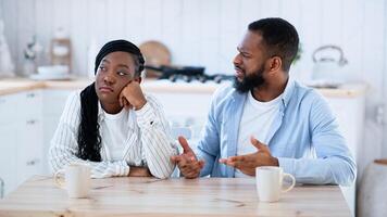 Marriage Crisis. Upset Black Woman Listening Complaints From Husband In Kitchen At Home, Young African American Man Blaming Wife For Problems In Relationship, Suffering Misunderstanding, Copy Space photo