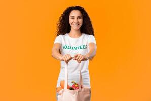 No More Plastic. Female Volunteer Showing White Eco Bag For Grocery Shopping Standing On Yellow Studio Background, Smiling To Camera. Consumerism And Ecology Concept photo