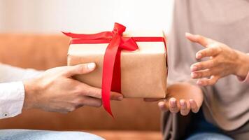 Muslim Husband Giving Gift Box To Wife, Closeup Of Hands, Celebrating Valentine's Day Together Sitting Indoors. Valentine And Birthday Holiday Celebration, Gifts And Presents. Cropped photo