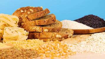 A variety of grains, pasta, and bread arranged against a bright blue background, highlighting textures and colors video