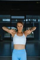 Woman performing upper body stretches in a modern fitness studio during a sunny afternoon session to enhance flexibility and relieve tension photo