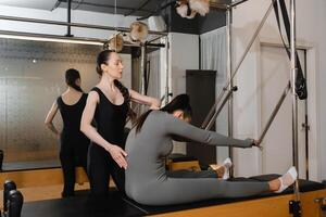 Pilates instructor guiding student on reformer machine during a private session in a modern studio photo