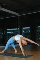 Yoga practitioner performs an advanced pose in a stylish training studio with floor-to-ceiling windows letting in natural light photo