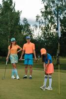 Family enjoys a fun day of golfing on a sunny afternoon at the course, with a youngster preparing to putt as parents watch and cheer photo
