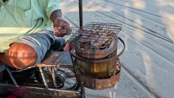 Vendor grilling squid on a portable charcoal grill. video