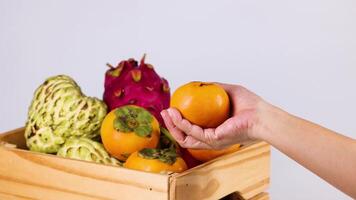 Hand tossing persimmon near assorted fruits video