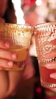 Two people clink glasses in a lively, warmly lit restaurant, creating a festive and joyful atmosphere video