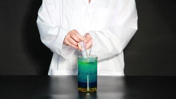 A scientist uses a syringe to mix colorful liquids in a jar, creating a dynamic visual experiment video