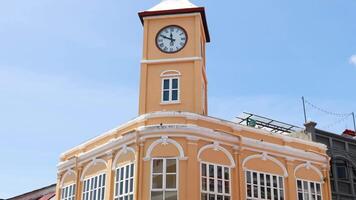 A clock tower stands tall in a sunny street scene as vehicles pass by, capturing urban life video