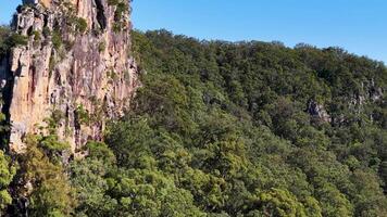 Aerial footage of Nimbin Rocks, showcasing lush greenery and rugged cliffs under bright daylight video