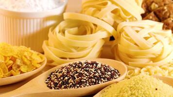 A close-up view of various grains and pasta arranged under warm lighting, highlighting textures and colors video
