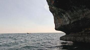 A kayaker paddles near a large rock formation. video