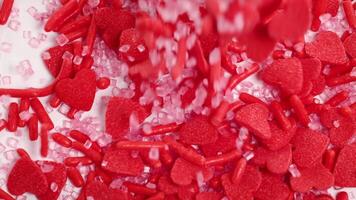 Red candy hearts and sprinkles cascade onto a white surface, creating a vibrant and playful visual effect video