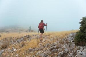 Hikers Exploring a Rocky Fog-Covered Mountain in the Morning Mist photo