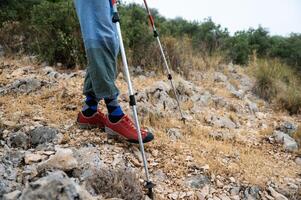 Exploration in Rocky Terrain. Hiker Trekking with Poles and Durable Shoes photo