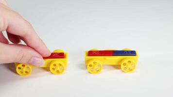 Hands manipulate colorful magnetic toy cars on a white surface, illustrating magnetic forces in a brightly lit setting video