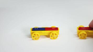 Hands manipulate magnetic toy cars on a white surface, illustrating magnetic attraction and repulsion with colorful blocks video