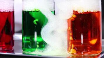 Vibrant liquids react with dry ice, creating colorful bubbling effects in a science experiment setting video