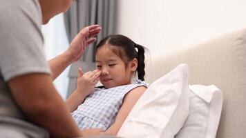A father cares for his sick daughter in a softly lit bedroom, checking her temperature and offering comfort video