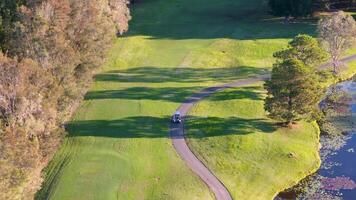 Drone footage captures a serene golf course landscape with a winding cart path, surrounded by lush greenery and trees video