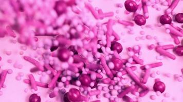 Macro view of pink candy sprinkles cascading onto a surface, creating a dynamic, colorful pattern video